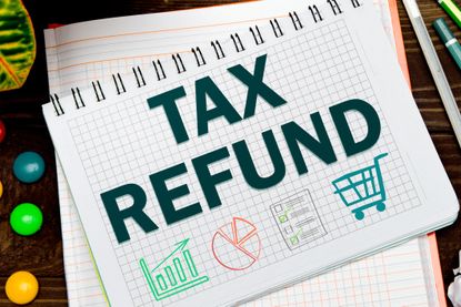 "tax refund" message written on a notebook beside office supplies.