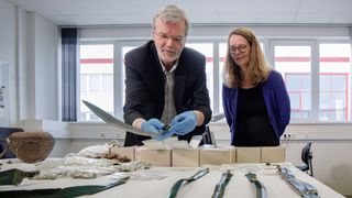 Two people inspect a collection of artifacts. 