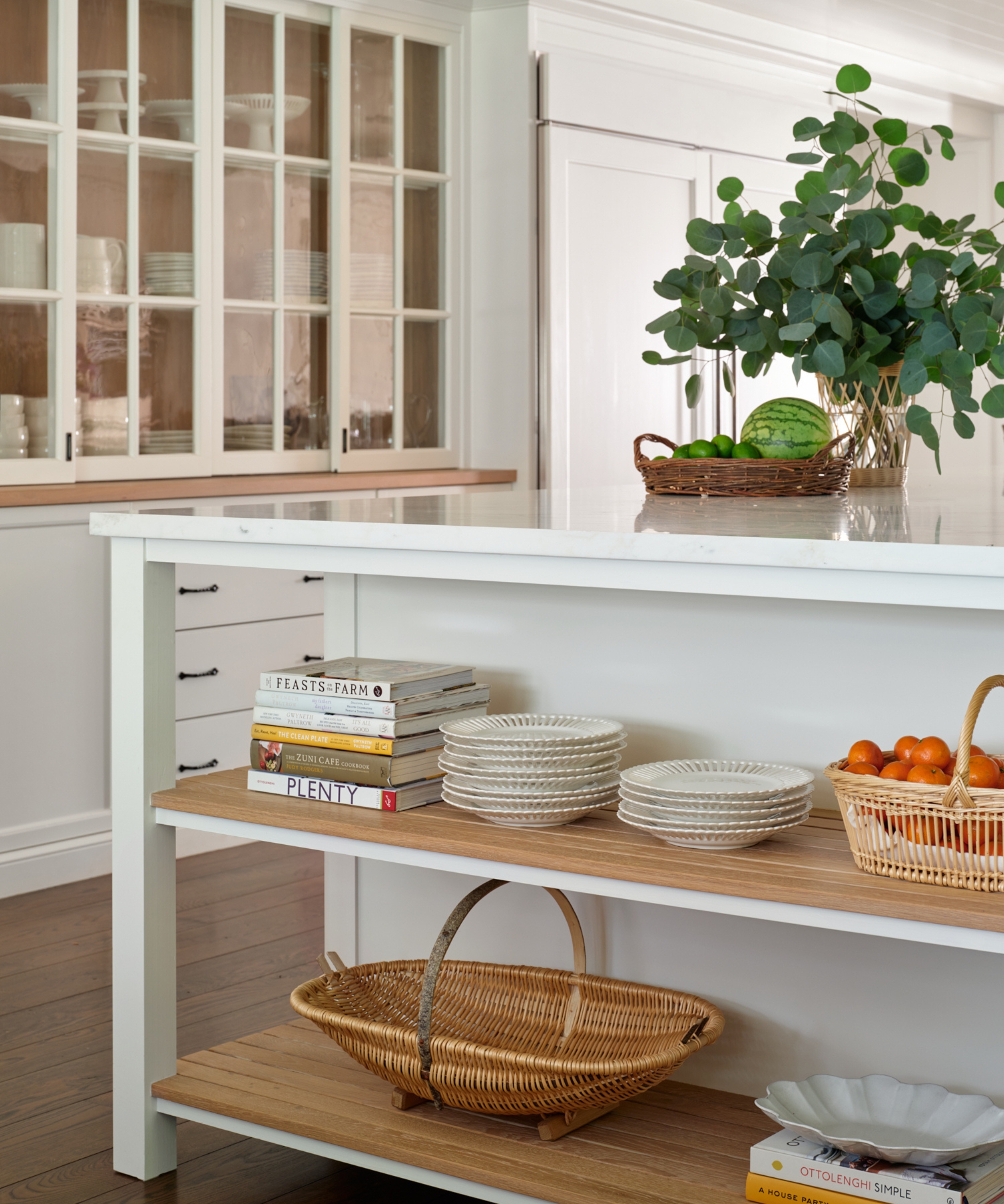 A white kitchen with an island feature open shelves at one end
