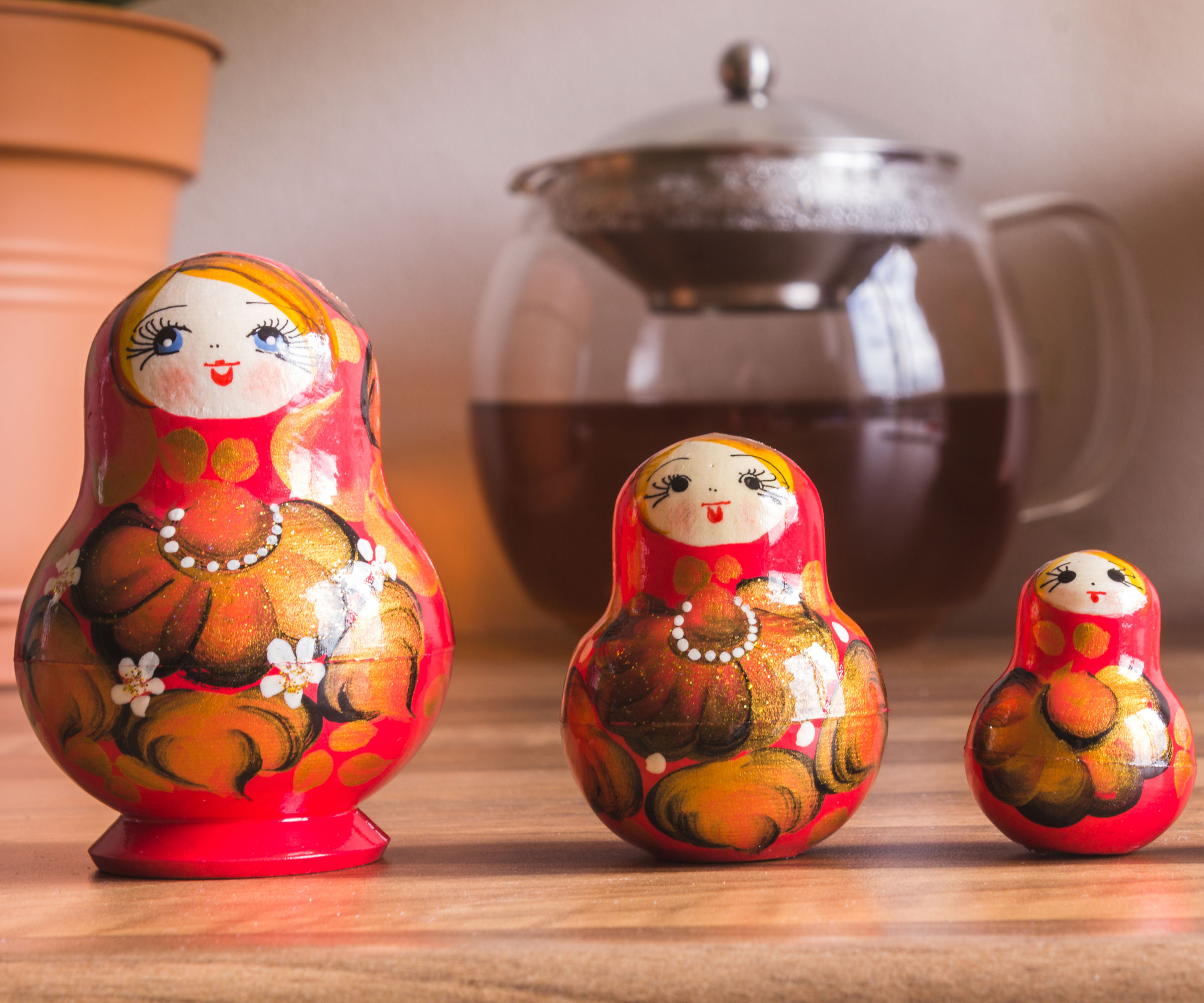 red Russian dolls in a line on worktop with plant pot