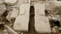 an ancient toilet made out of stone blocks and a hole in the ground