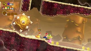Mario und seine Freunde rennen vor vor einer großen Stachelkugel in einem Wüsten-Level in Super Mario Bros. Wonder davon.