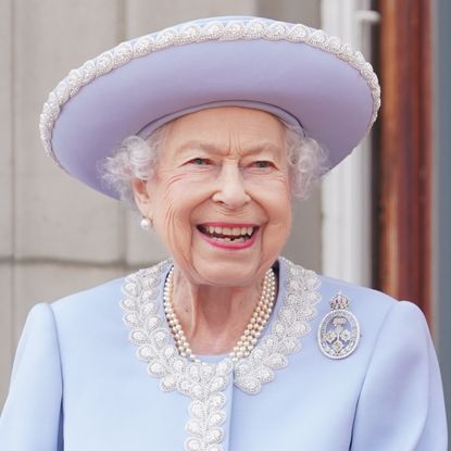 Queen Elizabeth wearing a blue coat and hat smiling