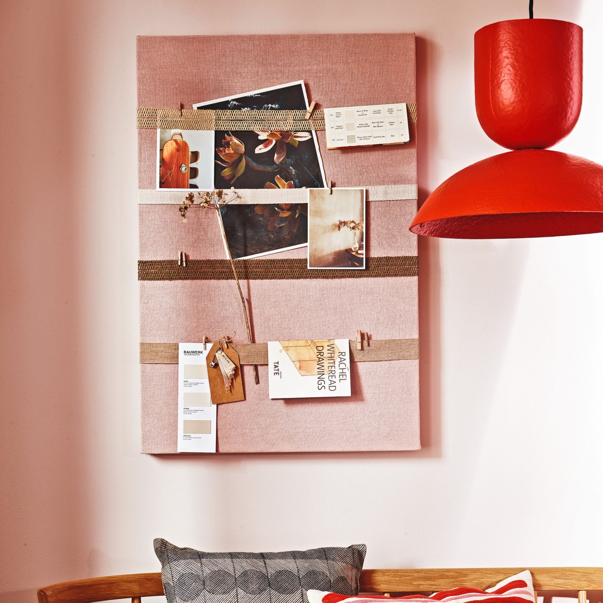 Orange painted wall with noticeboard and images pinned up next to light
