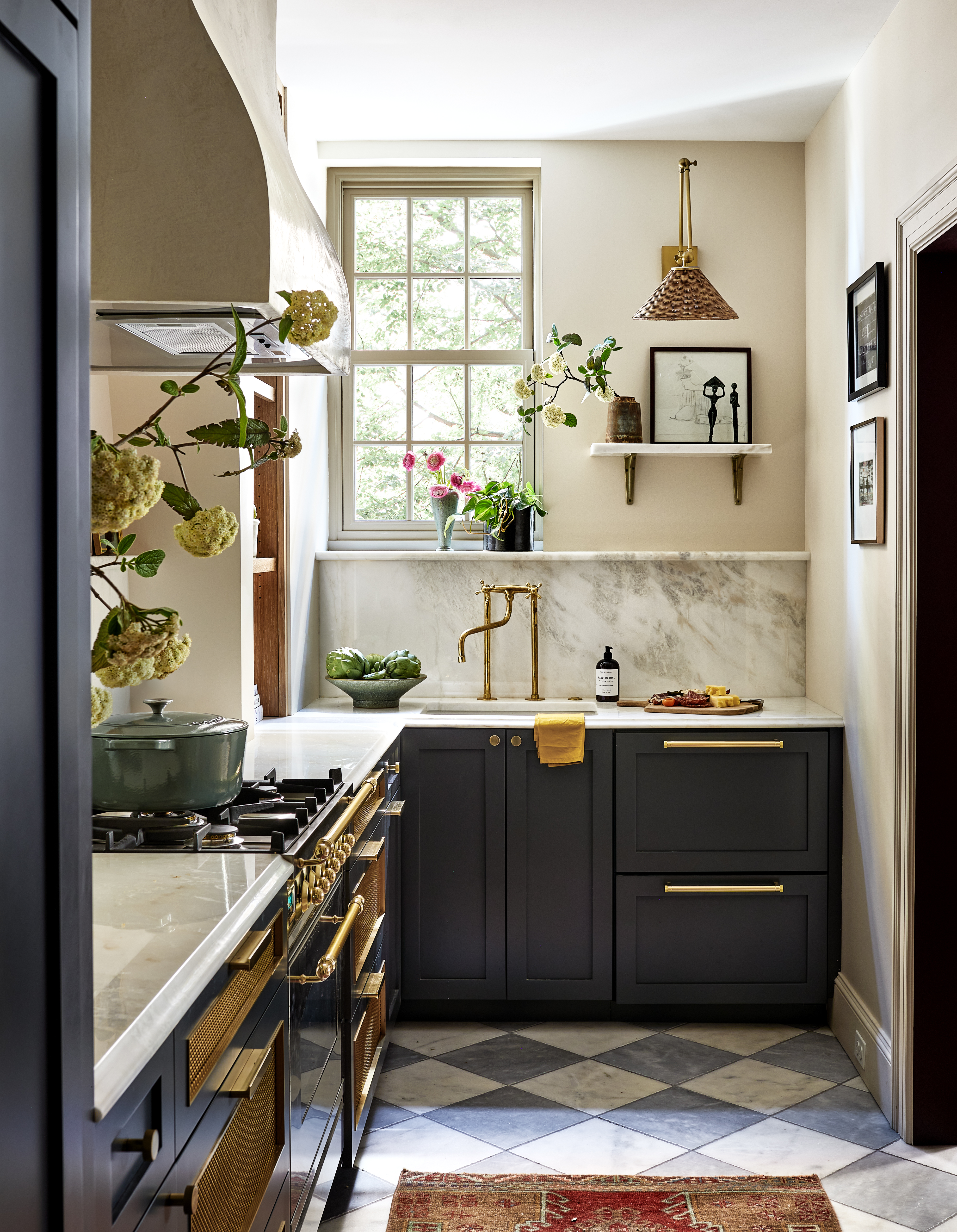 A small kitchen with marble backsplash, and gold hardware