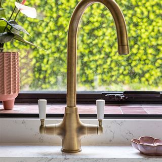 kitchen sink with brass tap and window