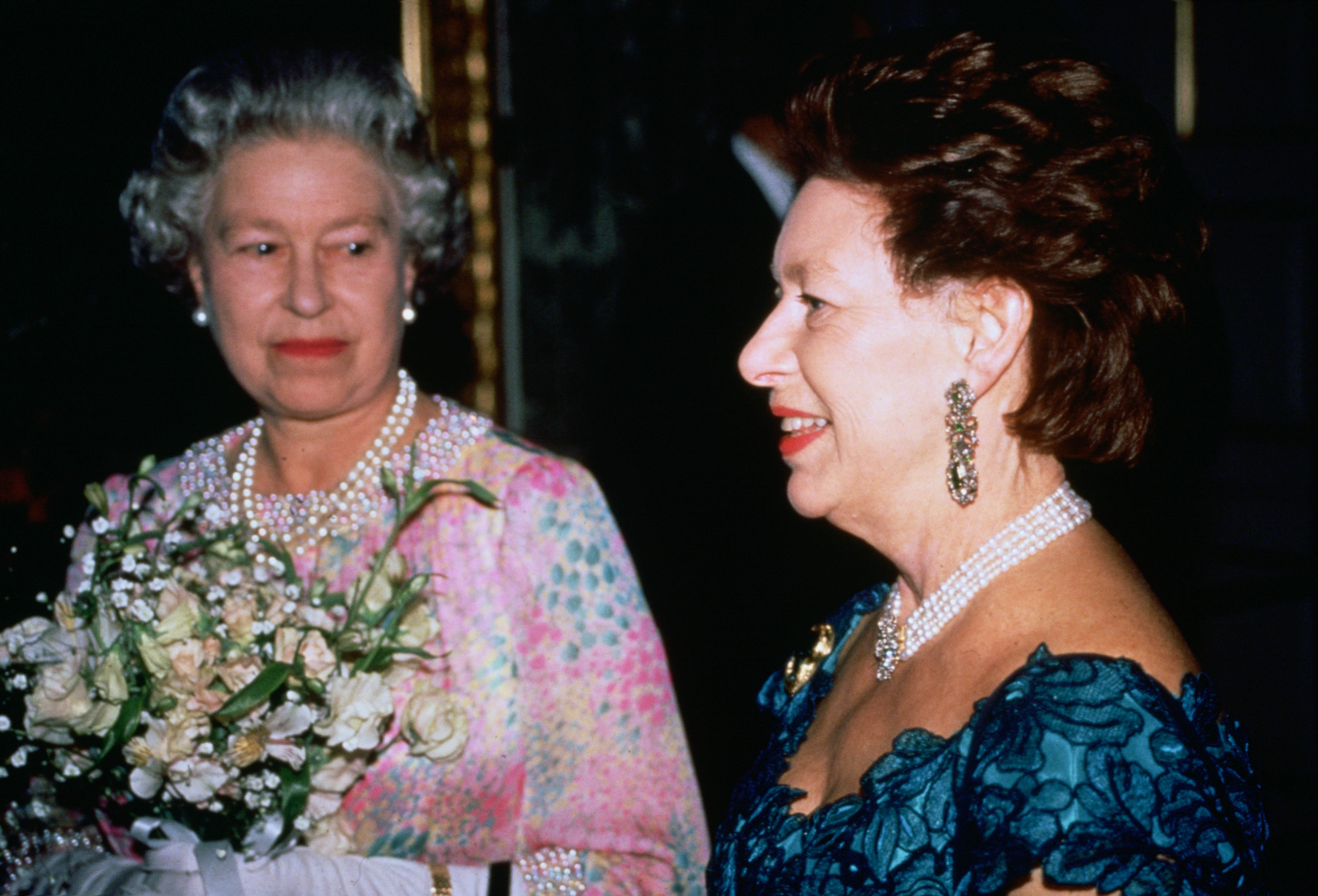 Queen Elizabeth holding flowers standing next to Princess Margaret
