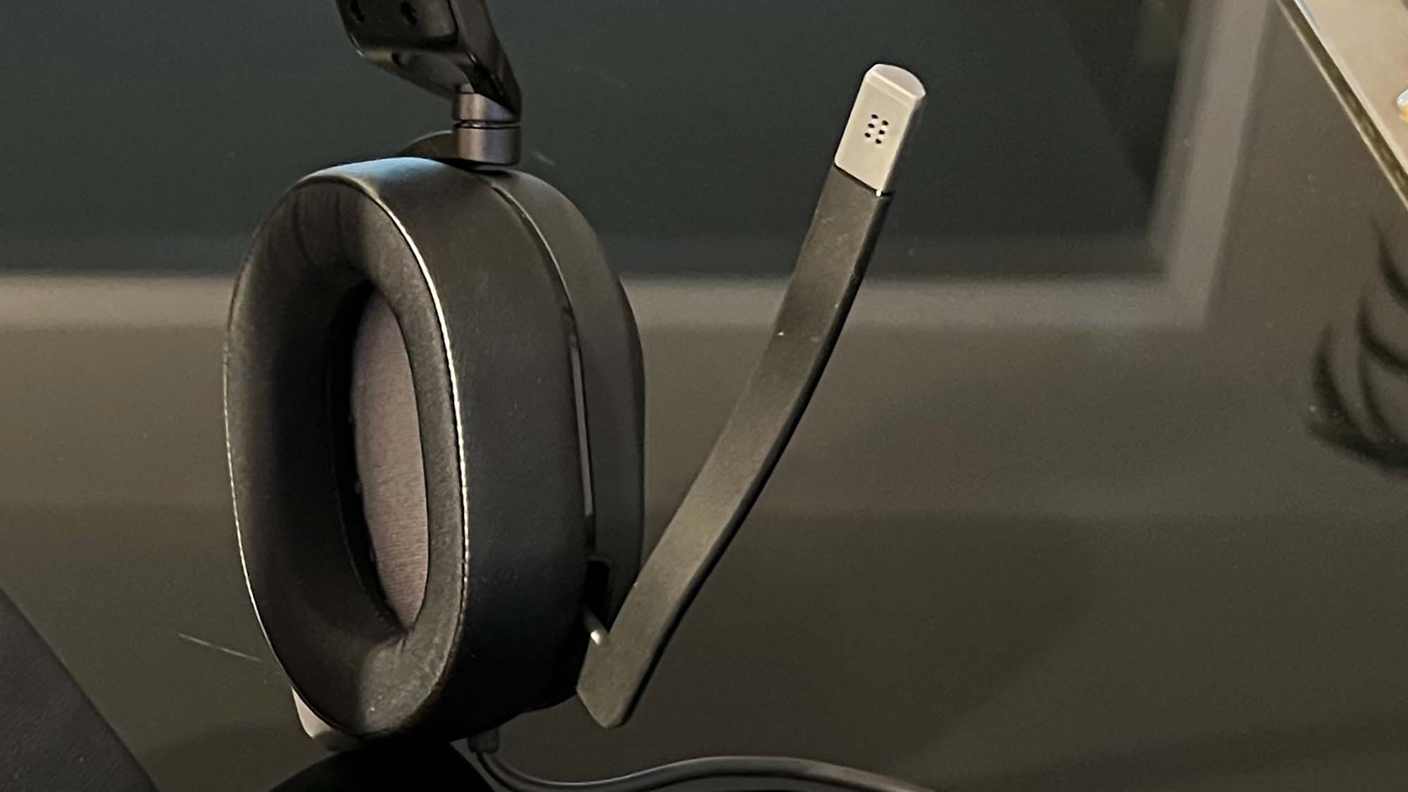 Um Corsair HS65 Surround em uma mesa preta reflexiva