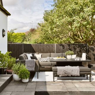 garden area with L shaped grey sofa and potted plants