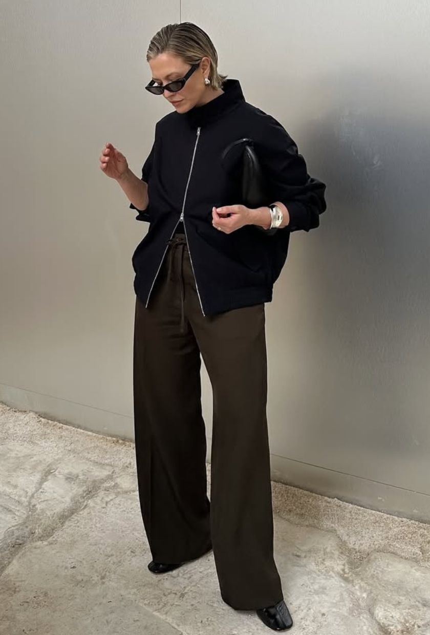 @alexisforeman wears a black bomber jacket, brown trousers, black patent ballet flats and sunglasses.