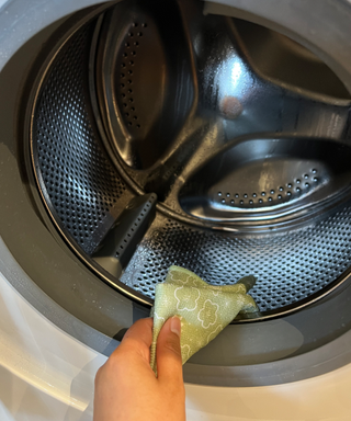 A green floral microfiber cloth cleaning a washing machine drum