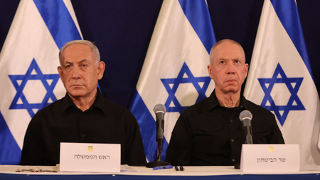 Benjamin Netanyahu and Defence Minister Yoav Gallant sit in front of Israeli flags at a press conference 