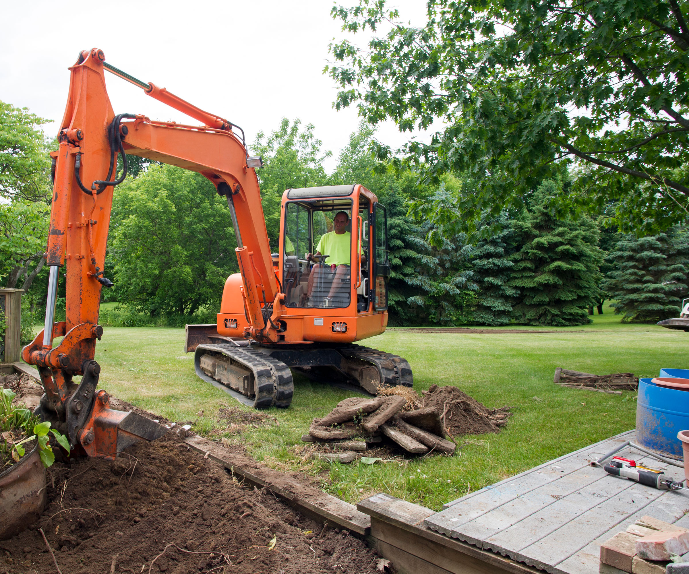 digger on lawn digging up soil and plants