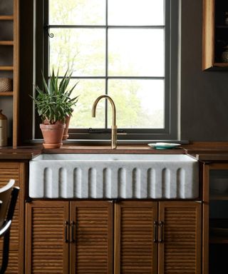 wooden kitchen with a marble fluted sink under the window and a quooker boiling water tap