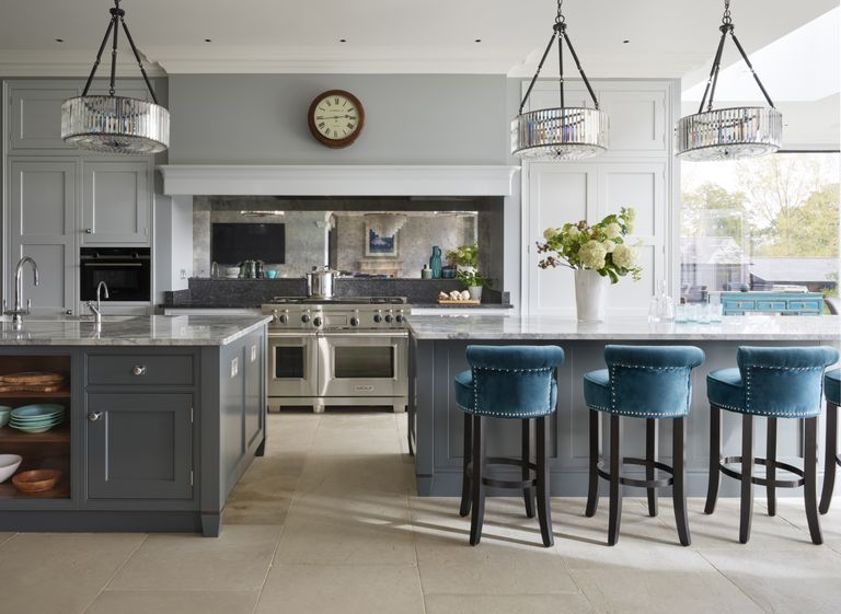 grey kitchen with two kitchen islands, blue bar stools, marble countertops