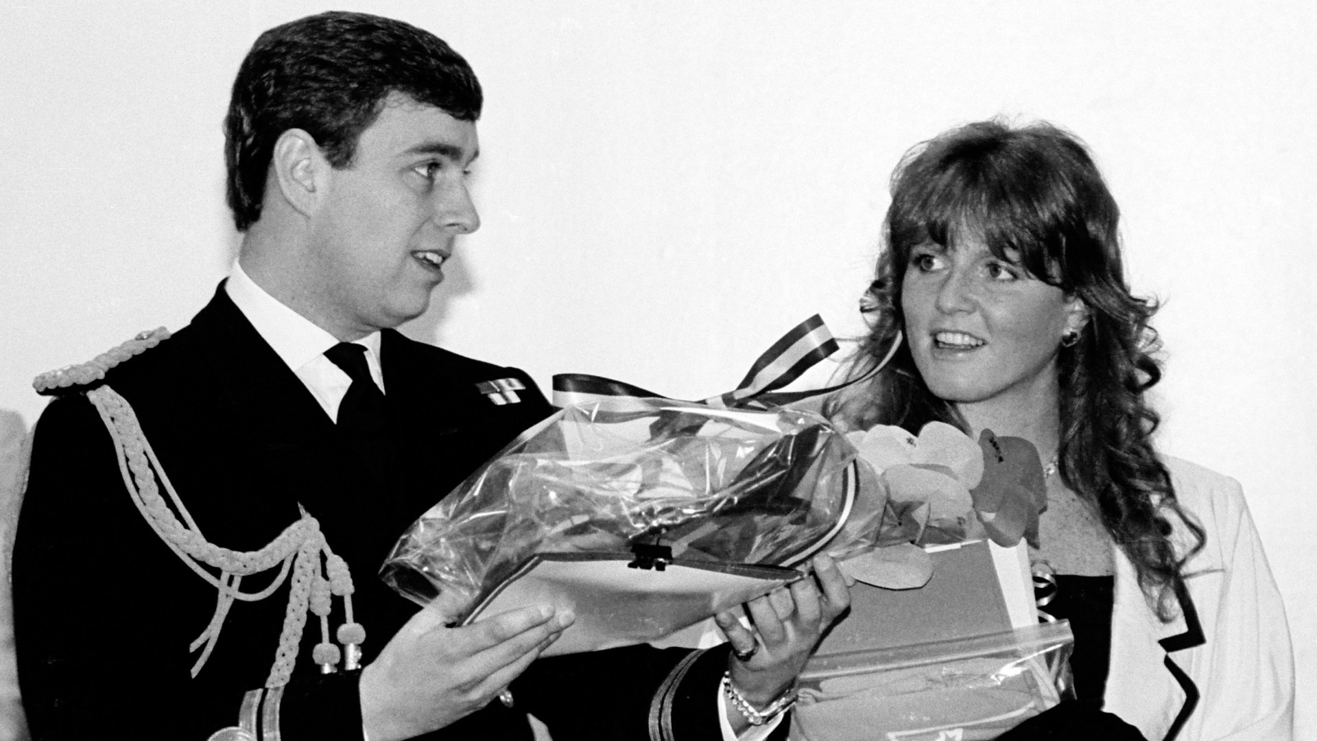 Prince Andrew wearing a naval uniform holding gifts smiling next to Sarah Ferguson 