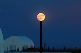 The supermoon appears to rest on top of a pole in this photo by Gandhi Kumar in Boulder, Colorado.