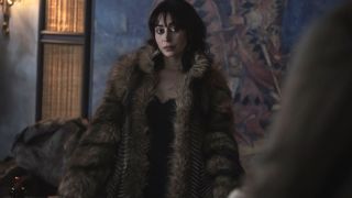 A grim looking Cristin Milioti stands wearing a fur coat in The Penguin.