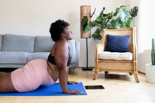 A woman doing pilates on a yoga mat in her home.