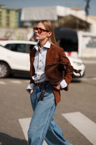 Frau in Wildlederjacke und Tasche.