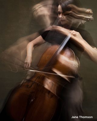 A cello player's movement is blurred through a long exposure