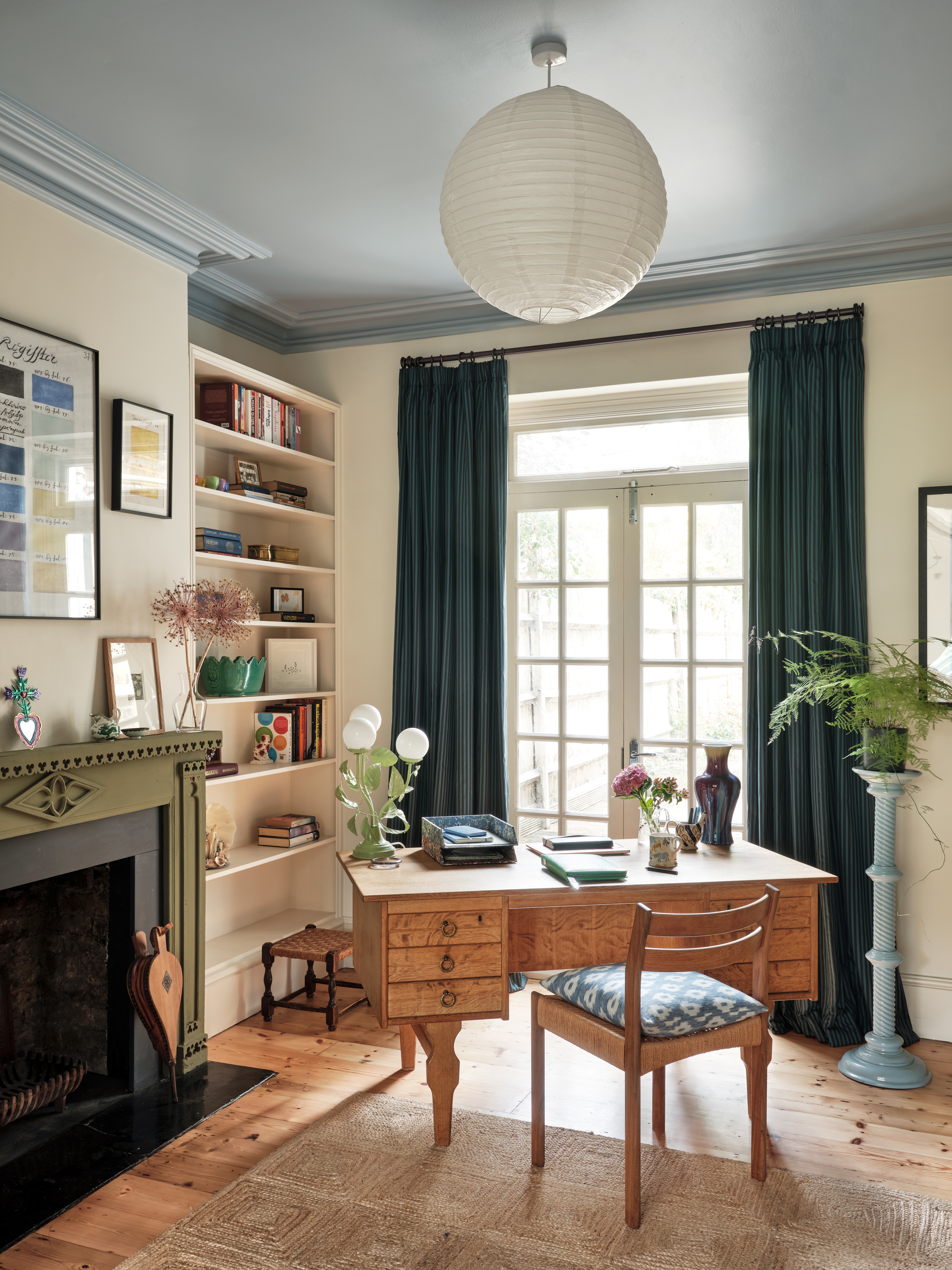 Interiors of a country-chic home with wooden floors, beige, pale blue, and rose pink walls, curated colorful artwork, and soft forms.