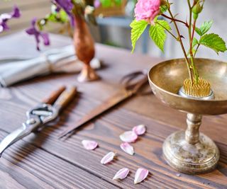 Kenzan in gold footed bowl, scissors and pruner on wooden table