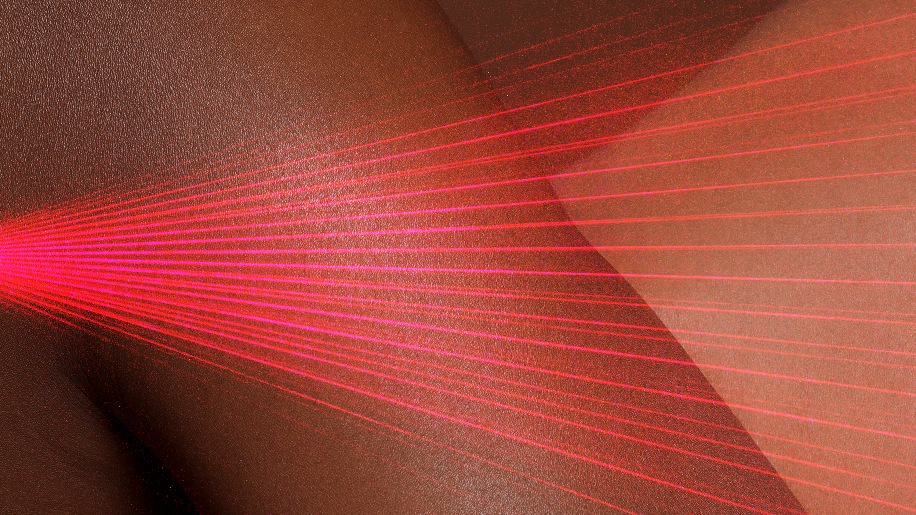 Melanin-rich skin close up with a red laser on top 