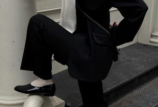 Christie Tyler wearing a suit, a silk top, socks, and patent leather Chanel moccasins.