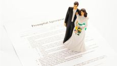 A bridge-and-groom figurine on top of a prenup agreement.