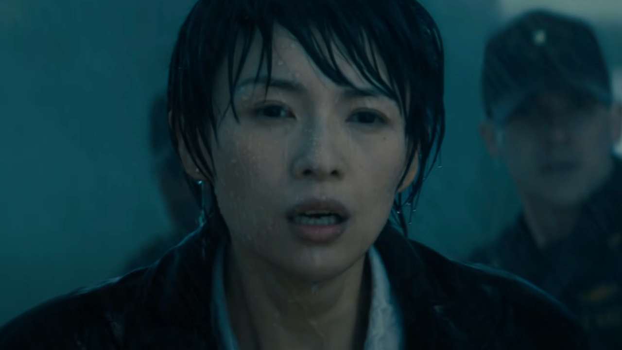 Zhang Ziyi stands in the rain looking shocked in Godzilla: King of the Monsters.