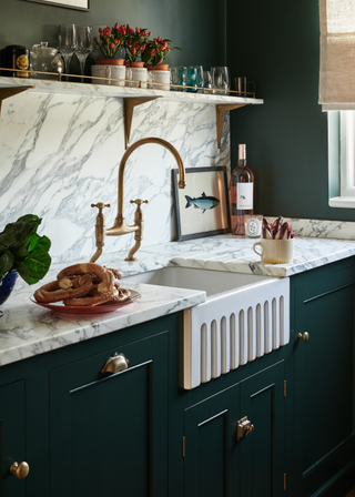 arabescato marble backsplash and counter top in a forest green kitchen