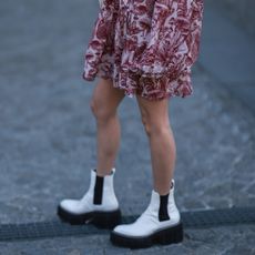  Xiayan Guo wearing a red short dress with floral design and white mesh and white leather Chelsea boots outside Stella McCartney during Paris Fashion Week on March 07, 2022 in Paris, France.