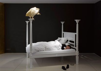 oversized ornate bed with a golden vulture perched on one of the bed posts