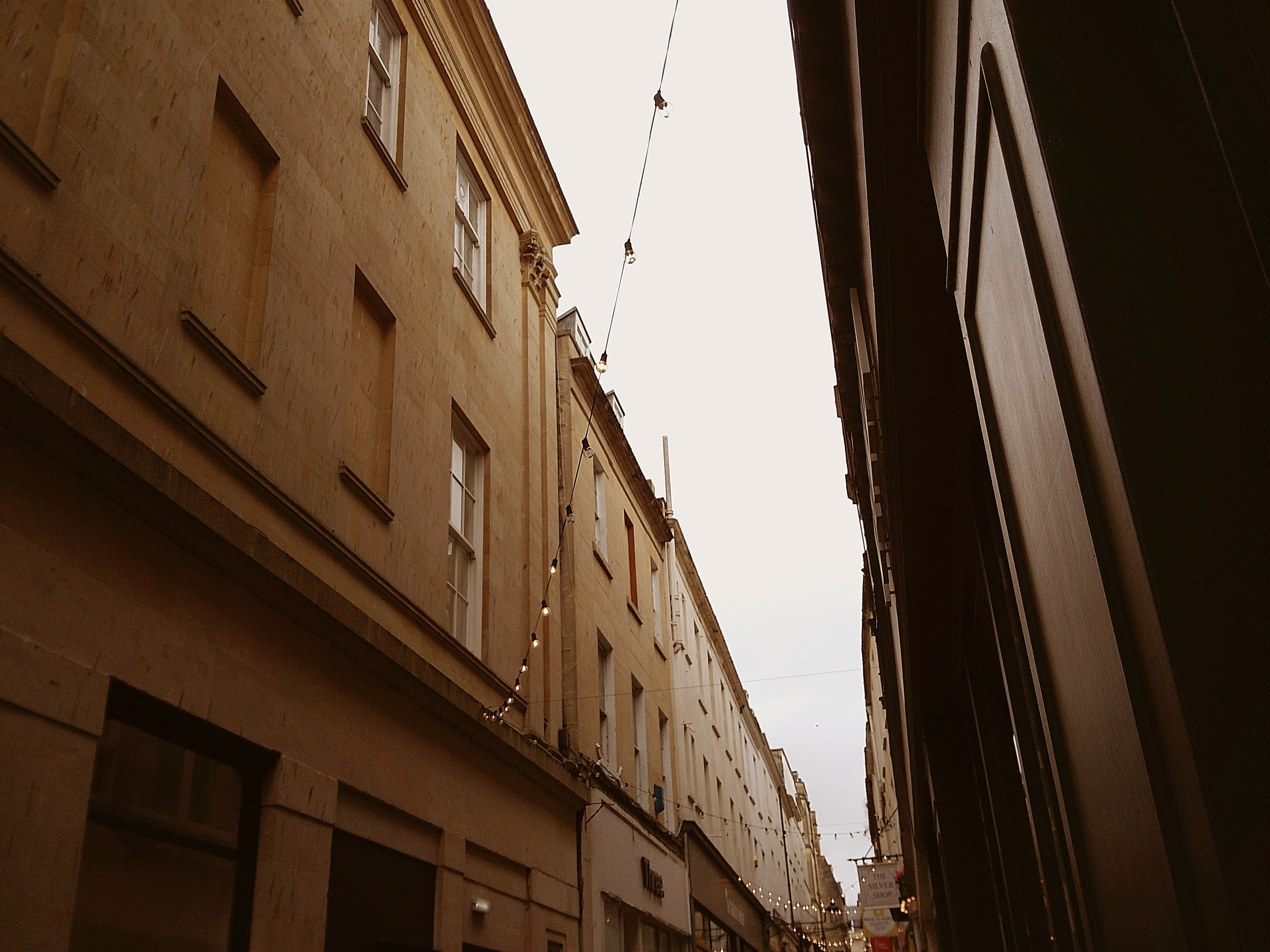 Sample image taken with Camp Snap 2 digital compact camera, showing upward view of narrow gap between buildings, with fairy lights strung across