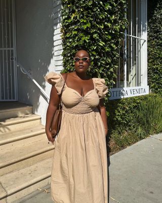 aniyah wears tan sun dress with puff sleeves and a brown handbag and sunglasses