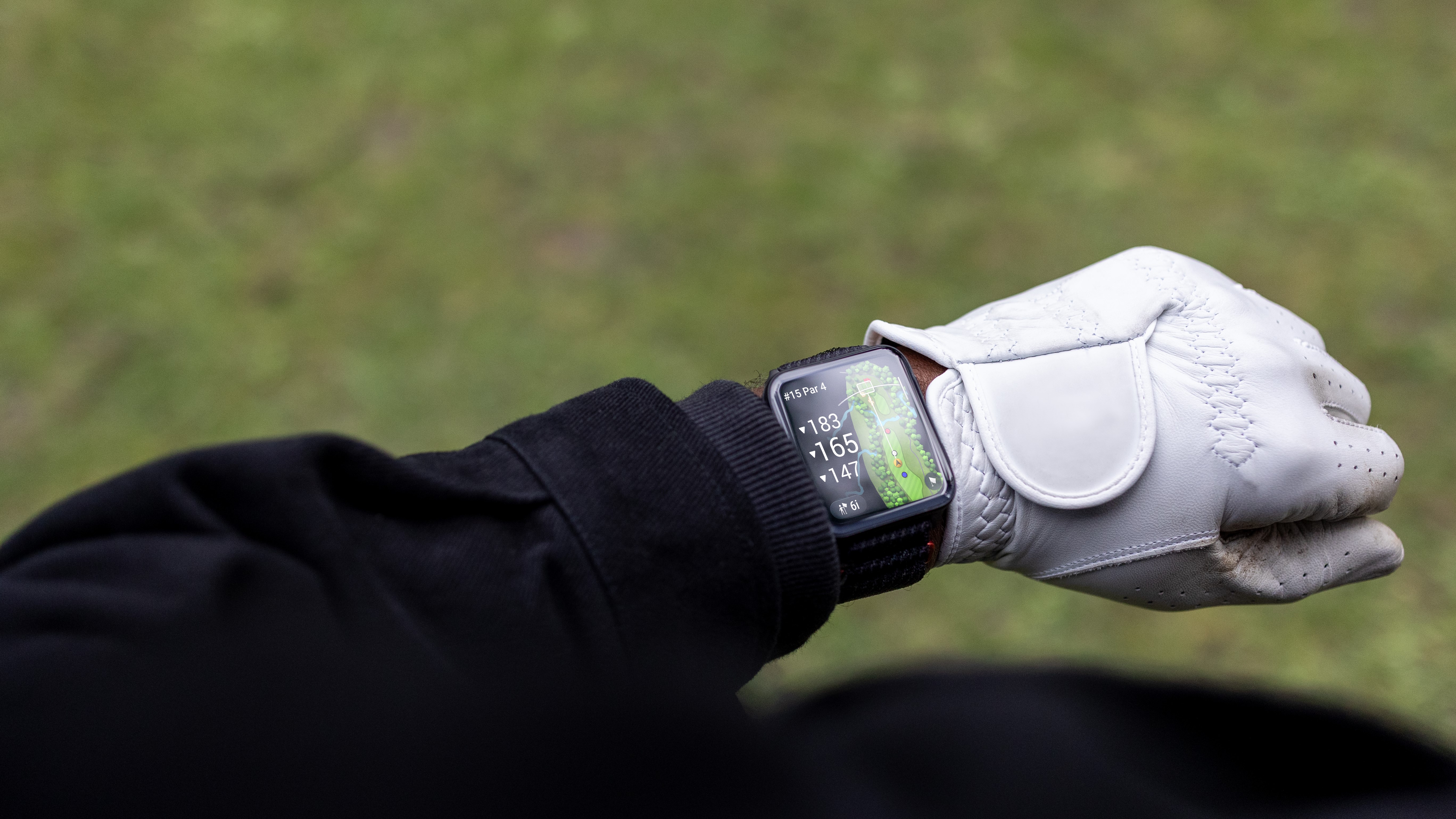 Photo of the Garmin Venu X1 worn by a golfer, the display showing golf course layout and distance data