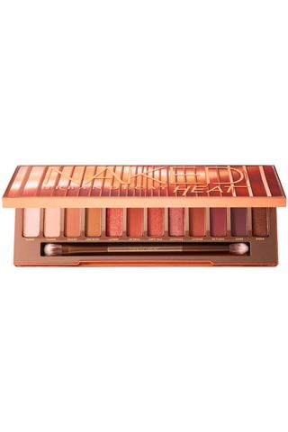 open Urban decay naked heat eyeshadow palette on a white background with dual-ended brush