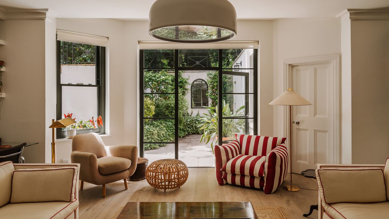 Living room with beige walls, beige chair and sofa, and red and white striped armchair