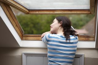 A woman leaning out of an attic window
