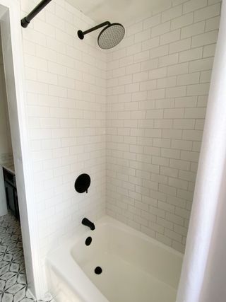 Refinished white bathtub with white show tile surround and black fittings