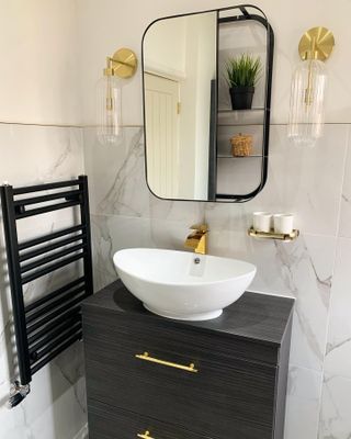 Made.com black mirror over white basin with black radiator and gilded faucets