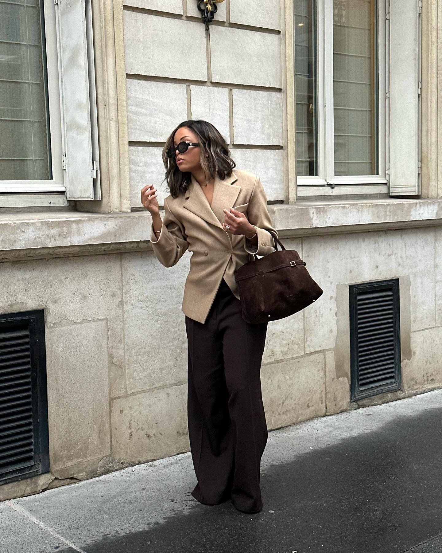 French influencer @slipintostyle walks down the street in Paris wearing a beige blazer and brown wide-leg trousers.