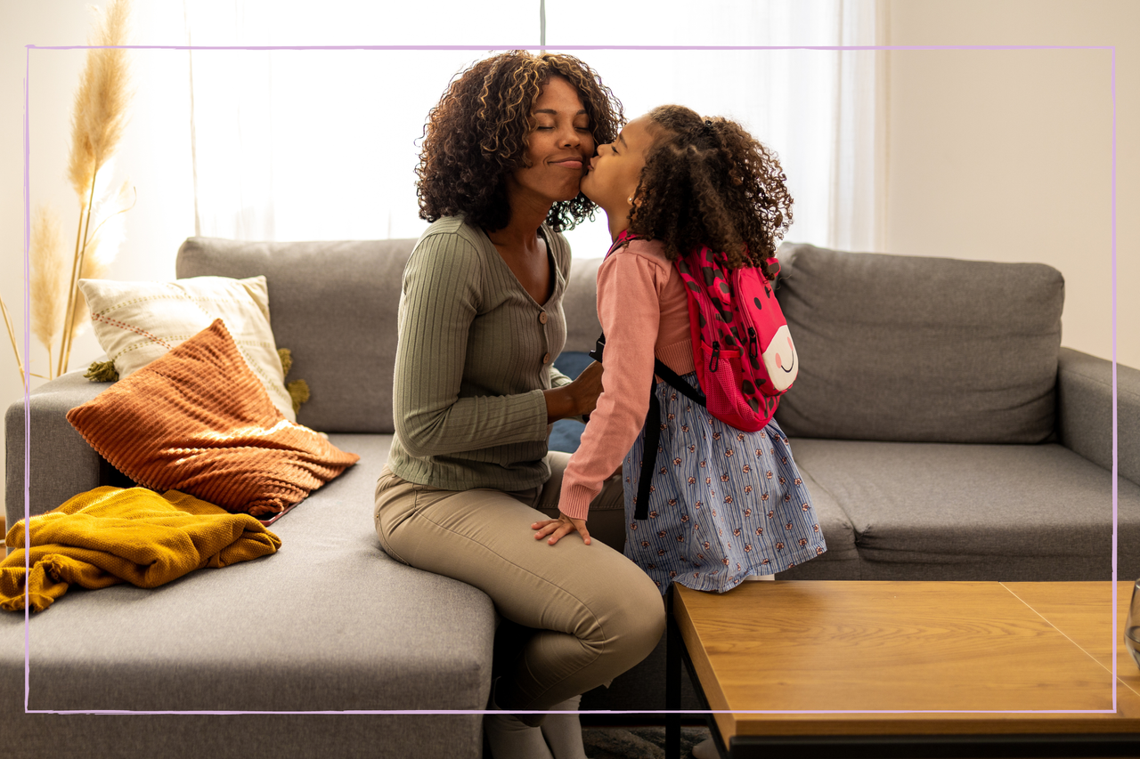 Young African American mother preparing her little daughter for school