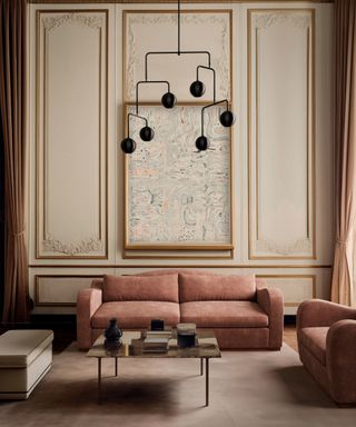 Living room with rust color sofa and armchair, coffee table and pendant light and pale wall paneling