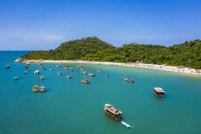 Aerial view of Campeche Island beach, Florianopolis, Santa Catarina, Brazil. A lot of boats sailing from Campeche beach to the little island in a sunny day.