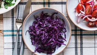 Red cabbage in a bowl sitting on a table cloth