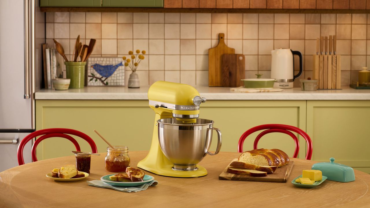 Yellow KitchenAid on wooden table with green kitchen