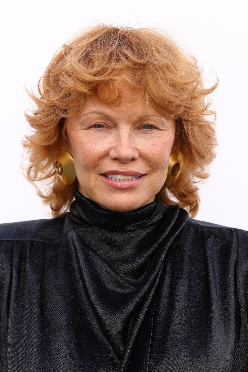 Pamela Anderson is pictured with soft copper hair, styled in tousled curls and wearing a black velvet dress at the Mugler Womenswear Spring/Summer 2026 show as part of Paris Fashion Week on October 02, 2025 in Paris, France.