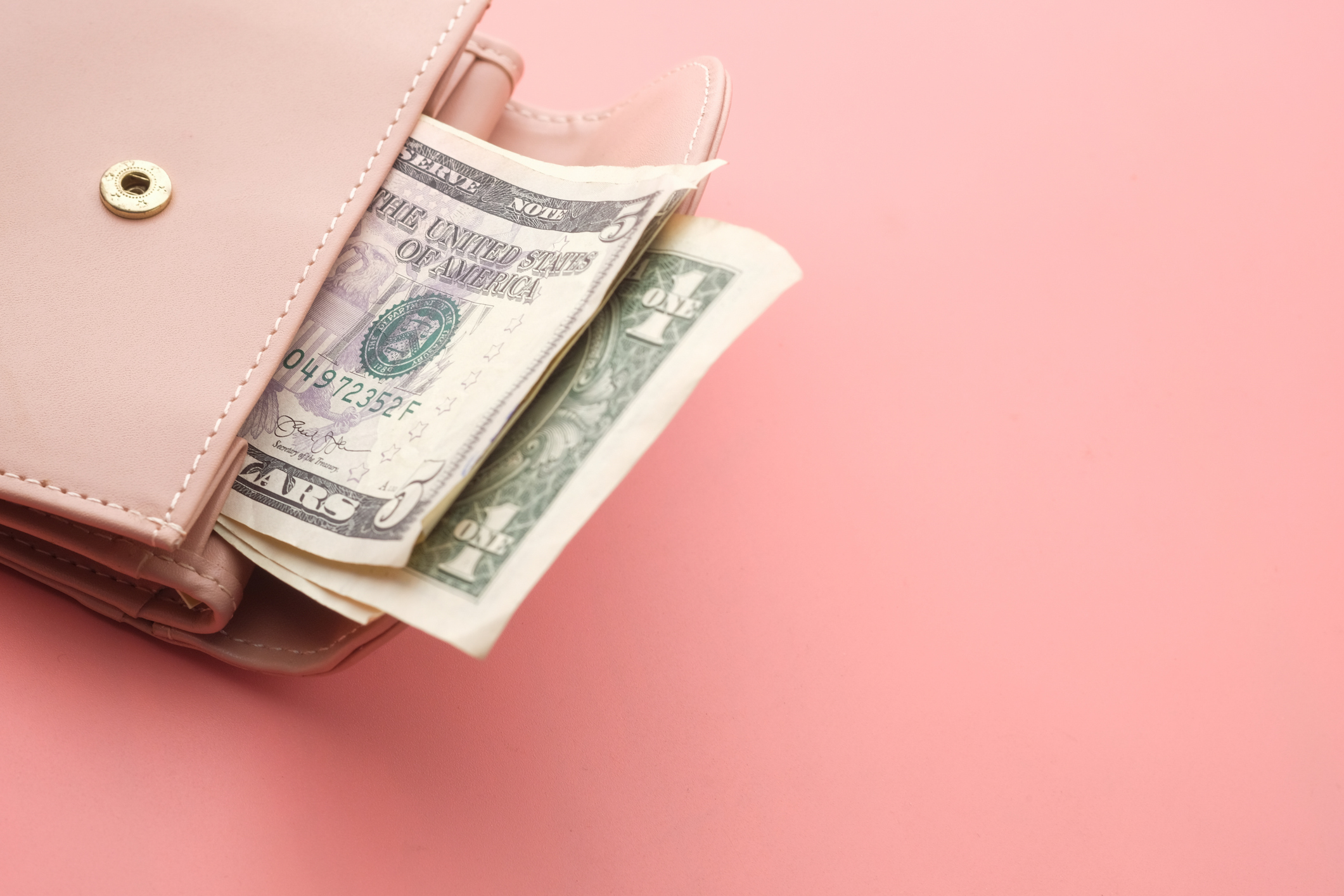 Pink wallet and US dollar banknotes on a pink background